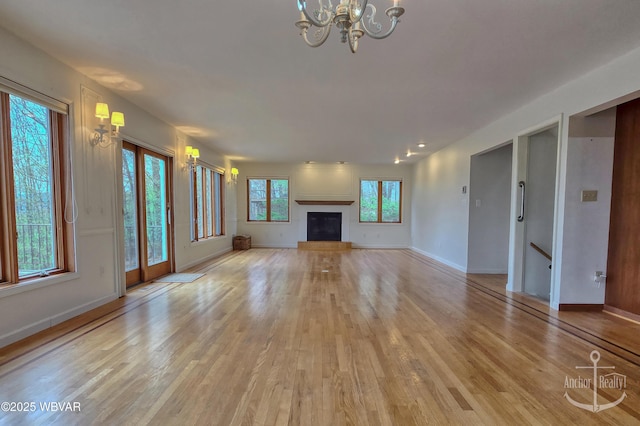 2312 Teaberry Ln, Lock Haven, PA 17745 - unfurnished living room featuring an inviting chandelier, a glass covered fireplace, light wood-style floors, and baseboards