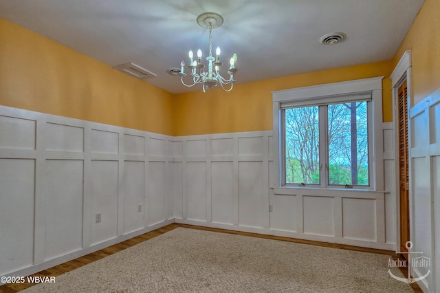2312 Teaberry Ln, Lock Haven, PA 17745 - empty room featuring a decorative wall, visible vents, a wainscoted wall, an inviting chandelier, and wood finished floors