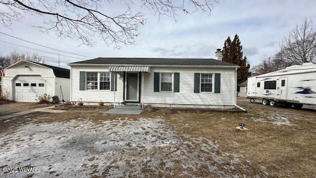 bungalow with an outbuilding, a detached garage, a chimney, and dirt driveway