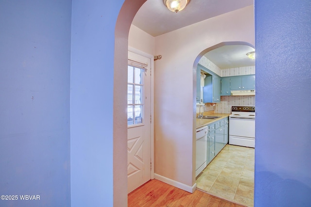 kitchen with sink, white appliances, backsplash, light hardwood / wood-style floors, and blue cabinets