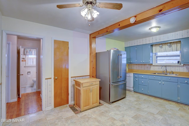 kitchen featuring sink, stainless steel fridge, blue cabinetry, dishwasher, and wood counters