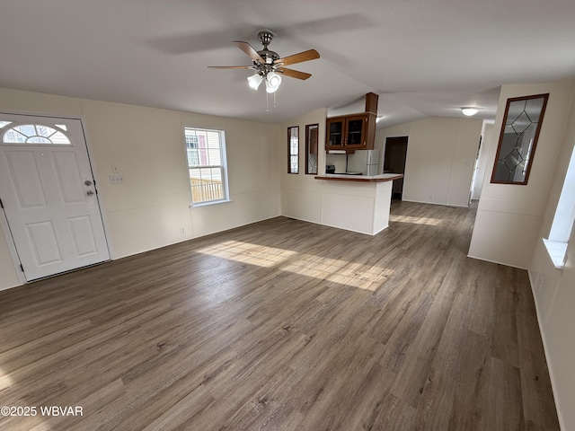 unfurnished living room with dark hardwood / wood-style floors, ceiling fan, and vaulted ceiling