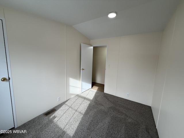 spare room featuring carpet and vaulted ceiling