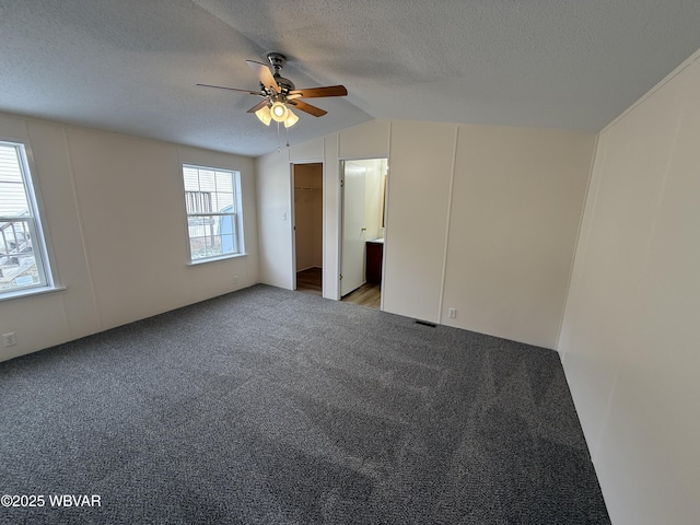 carpeted spare room featuring a textured ceiling, ceiling fan, and lofted ceiling