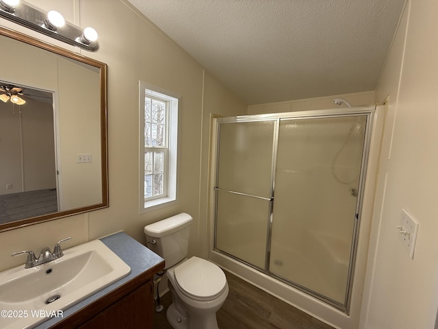 bathroom with hardwood / wood-style floors, vanity, toilet, a textured ceiling, and a shower with shower door