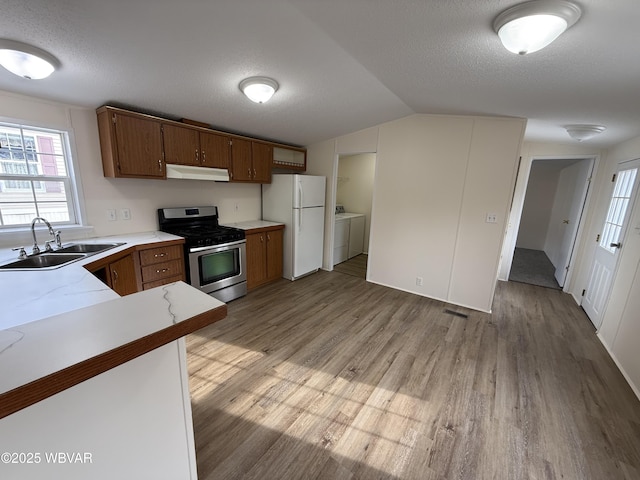 kitchen featuring gas stove, sink, light hardwood / wood-style flooring, white fridge, and washer and dryer