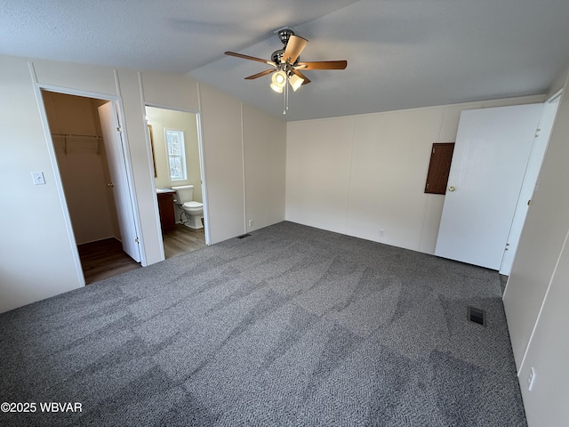 unfurnished bedroom featuring a walk in closet, ensuite bath, carpet flooring, ceiling fan, and a closet