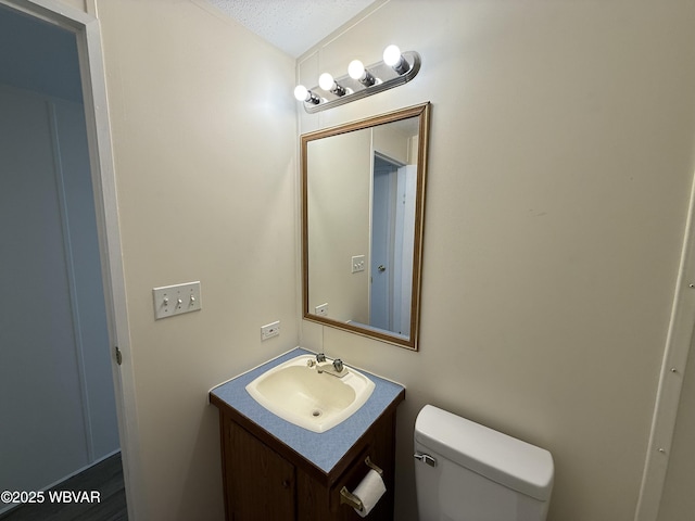 bathroom featuring vanity, a textured ceiling, and toilet