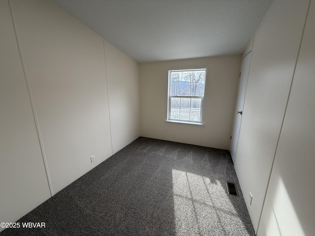 carpeted empty room with a textured ceiling