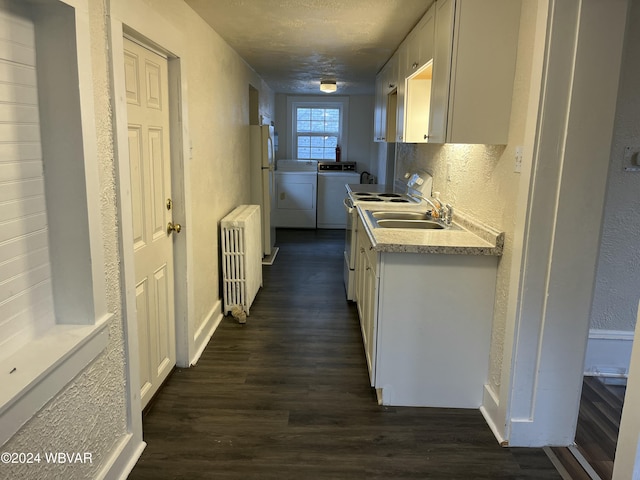 kitchen featuring dark hardwood / wood-style floors, white cabinetry, radiator, and washing machine and clothes dryer