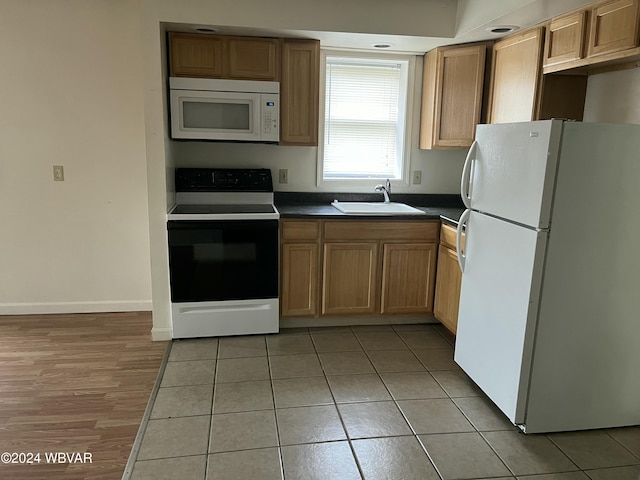 kitchen with light tile patterned flooring, white appliances, and sink