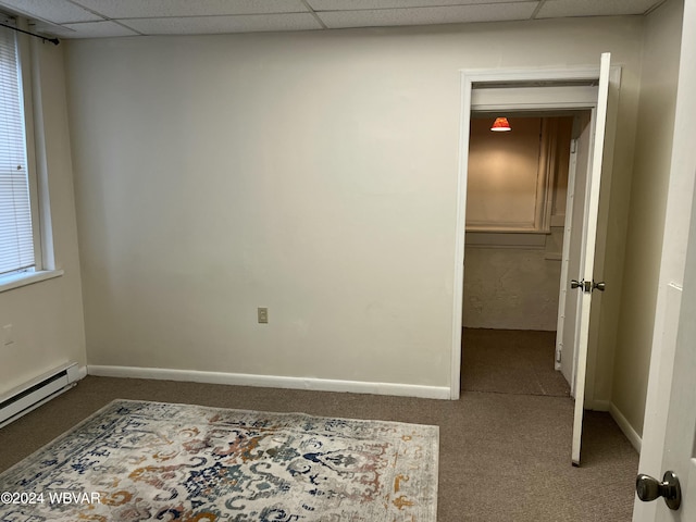 carpeted spare room with a paneled ceiling and a baseboard radiator