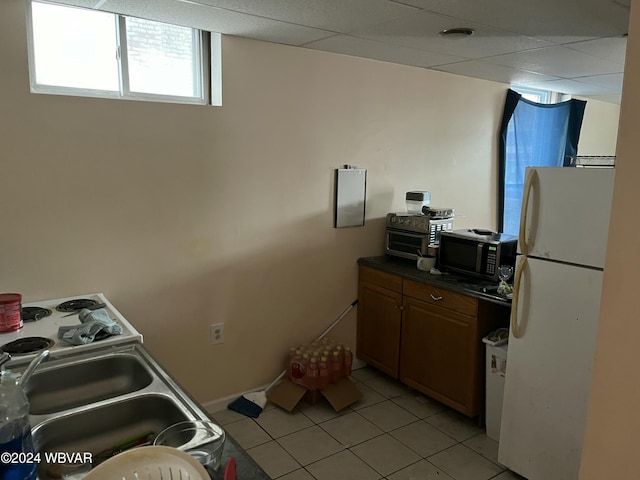 kitchen with a paneled ceiling, white fridge, and light tile patterned floors