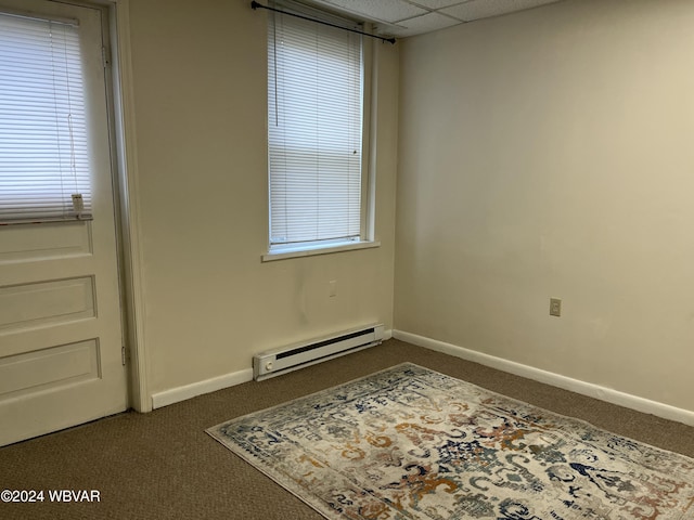 carpeted spare room with a paneled ceiling and a baseboard radiator