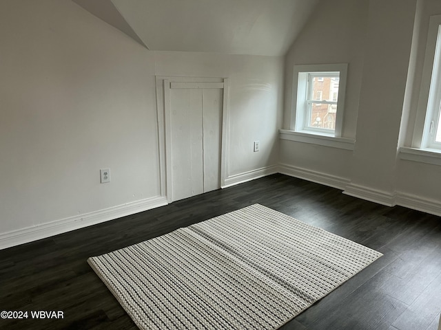 unfurnished bedroom with dark hardwood / wood-style flooring, lofted ceiling, and a closet