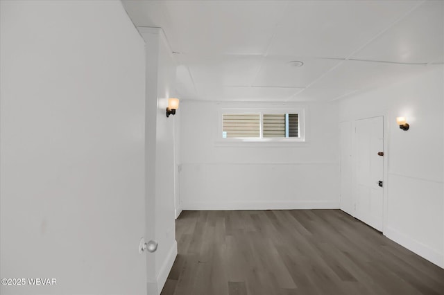 spare room with baseboards and dark wood-style flooring