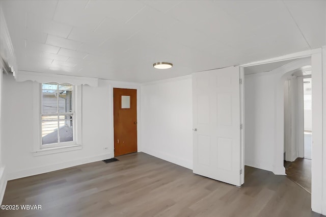 interior space featuring baseboards, arched walkways, and wood finished floors