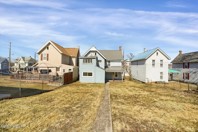 rear view of property featuring a lawn, fence, a residential view, and metal roof