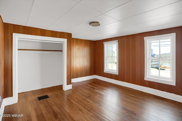 unfurnished bedroom with visible vents, multiple windows, a closet, and hardwood / wood-style floors