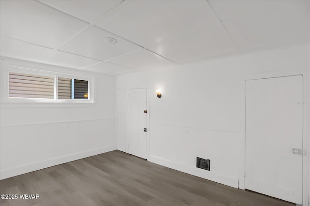 basement with a drop ceiling, baseboards, and wood finished floors