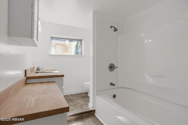 bathroom featuring tile patterned floors, toilet, vanity, baseboards, and shower / bathtub combination