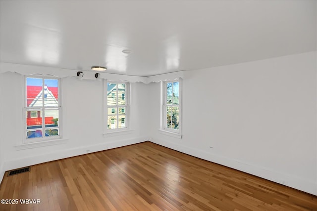 empty room featuring visible vents, baseboards, and wood finished floors