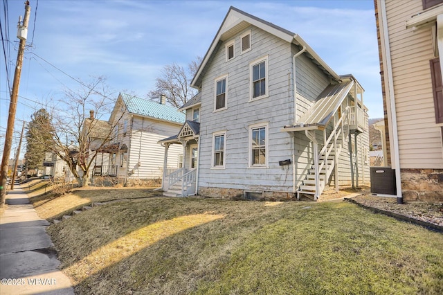 exterior space featuring central air condition unit, a lawn, and entry steps