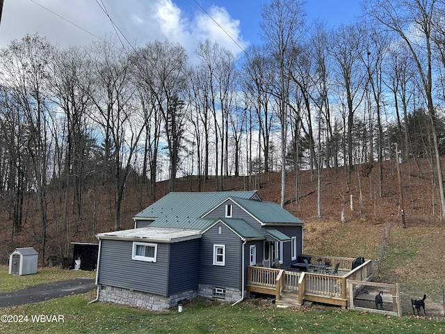 back of house with a storage unit and a wooden deck