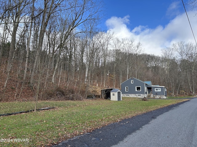 view of front of house featuring a storage shed and a front yard