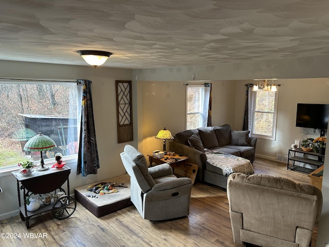 living room featuring wood-type flooring, a healthy amount of sunlight, and a notable chandelier