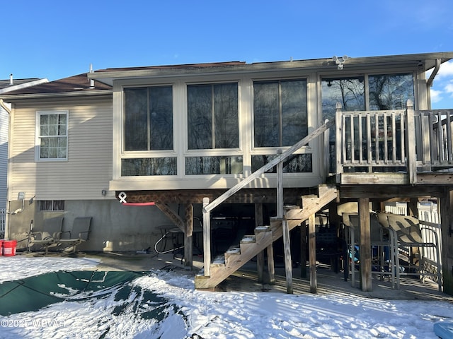 snow covered back of property with a pool side deck