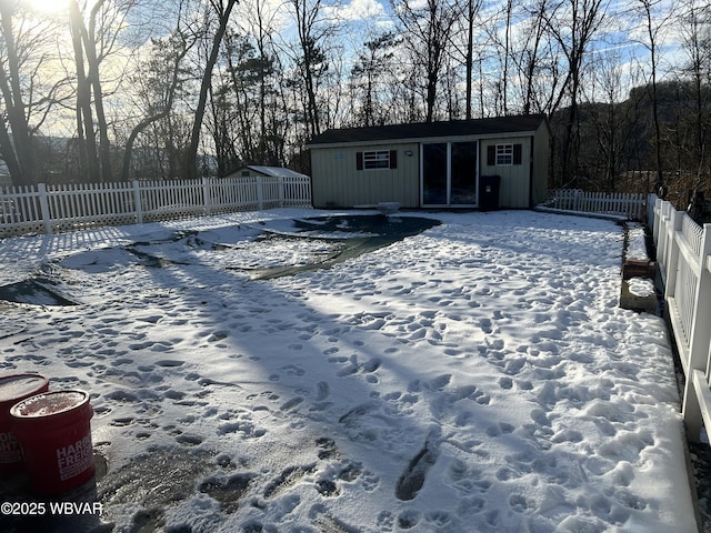 snow covered rear of property featuring an outbuilding