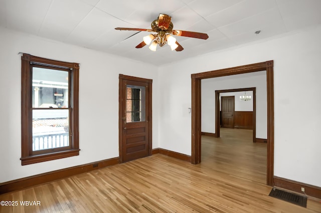 spare room featuring ceiling fan with notable chandelier and light wood-type flooring