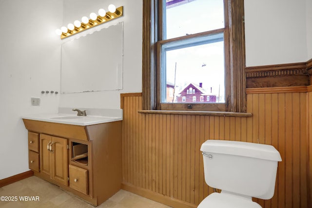 bathroom with wooden walls, vanity, and toilet