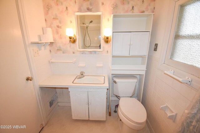 bathroom with a wainscoted wall, wallpapered walls, toilet, and tile walls