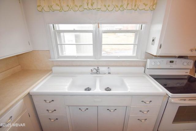 kitchen with light countertops, a sink, white range with electric stovetop, and white cabinets