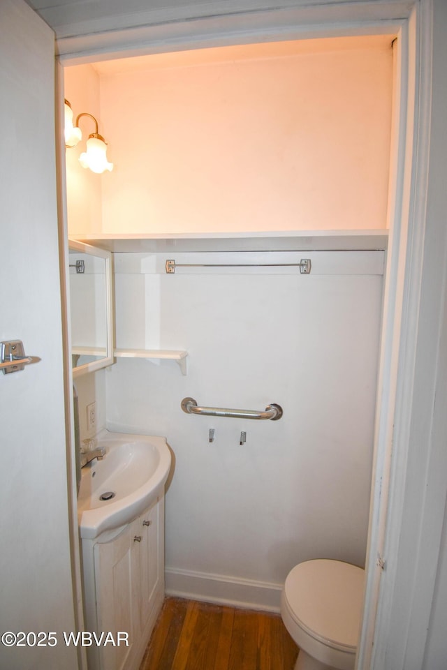 bathroom with toilet, baseboards, wood finished floors, and vanity