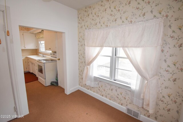 interior space with wallpapered walls, baseboards, visible vents, light colored carpet, and a sink