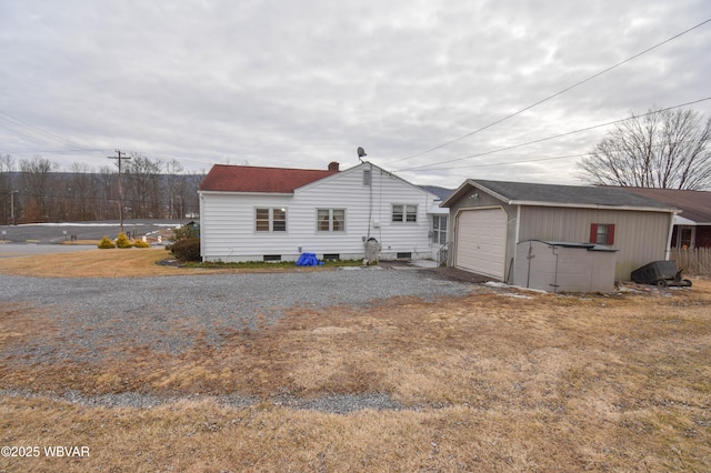 back of property with a garage, gravel driveway, and an outdoor structure