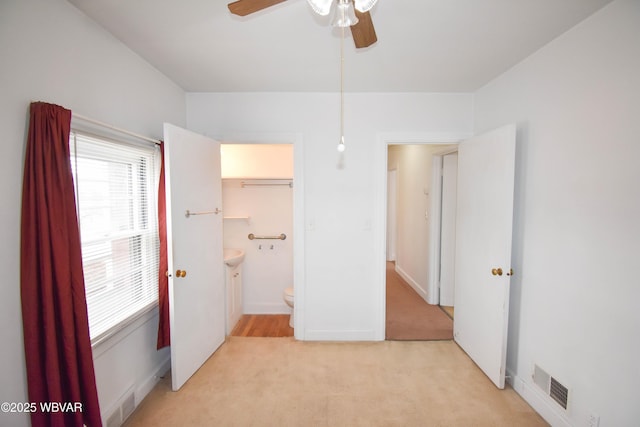 unfurnished bedroom featuring light carpet, visible vents, and a ceiling fan