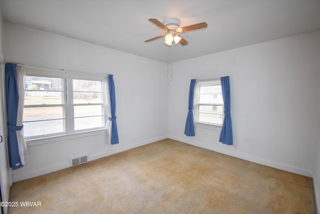 empty room with light carpet, baseboards, visible vents, and a ceiling fan