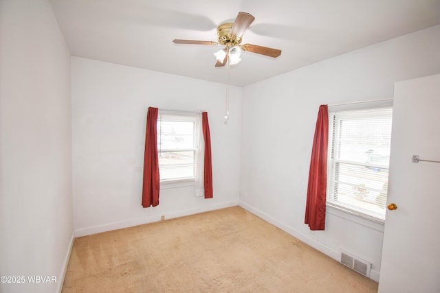 empty room with light carpet, baseboards, visible vents, and a ceiling fan