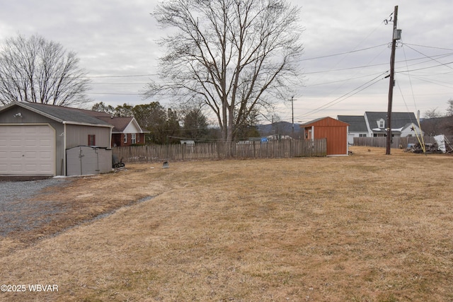 view of yard with a detached garage, fence, and an outdoor structure