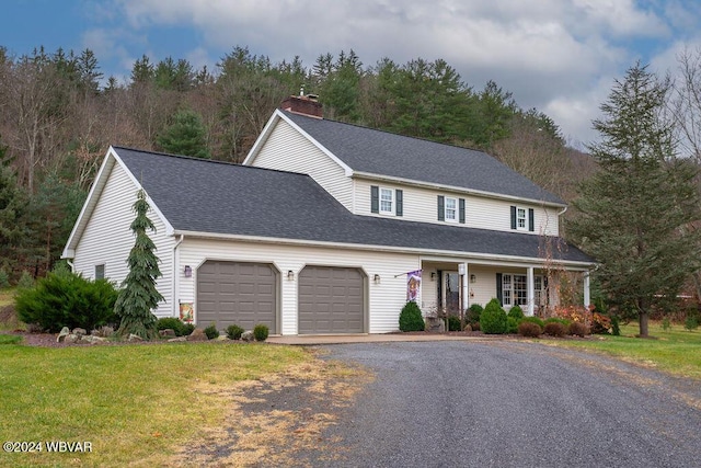 view of front of home with a front yard, a porch, and a garage