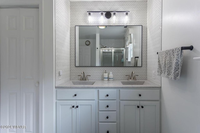 bathroom featuring decorative backsplash, vanity, and a shower with shower door