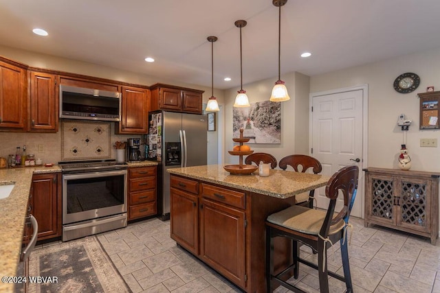 kitchen with pendant lighting, backsplash, a kitchen breakfast bar, a kitchen island, and stainless steel appliances