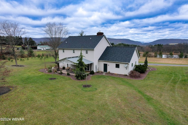 rear view of house with a mountain view and a lawn