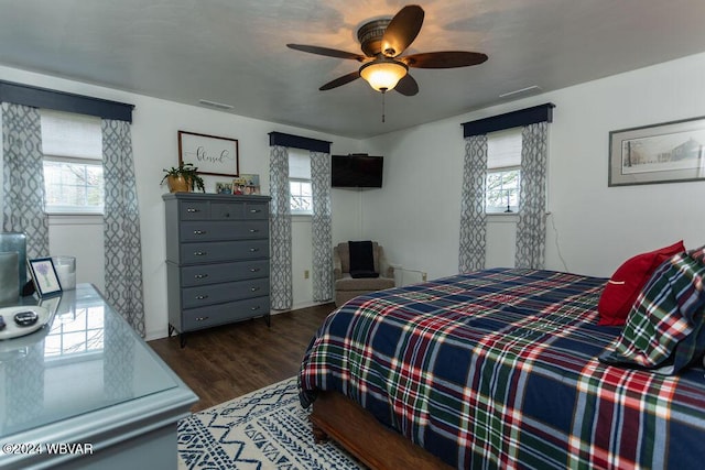 bedroom with multiple windows, ceiling fan, and dark hardwood / wood-style flooring