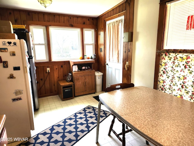 dining area featuring light floors, wood walls, and a healthy amount of sunlight