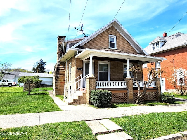 bungalow-style home featuring covered porch, a chimney, brick siding, and a front yard